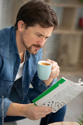 concentrated man reading business newspaper and holding coffee cup