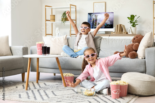 Cute happy friends with popcorn and soda watching cartoons on sofa at home