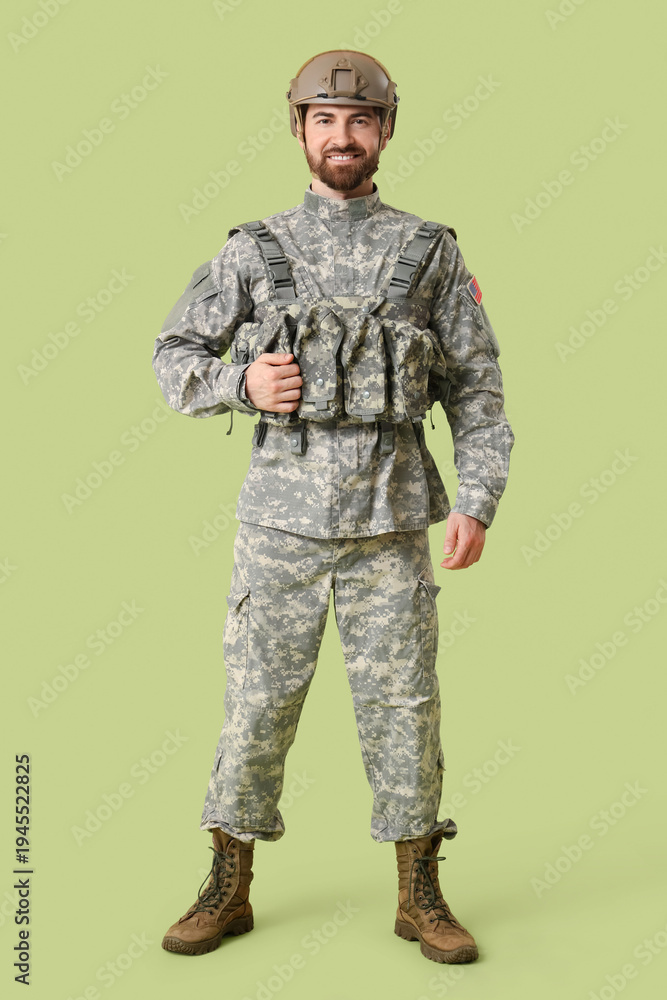 Obraz premium Young happy male soldier in uniform on green background