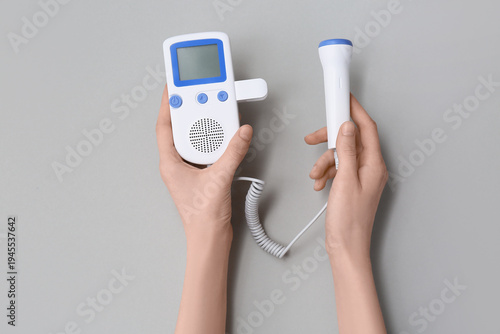 Obraz na płótnie Female hands with fetal doppler on grey background