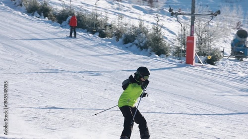 Young skier riding downhill on snowy slope in slow motion at sunny mountain ski resort
