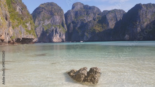Crystal clear turquoise waters and dramatic limestone cliffs surrounding the famous Maya Bay in Phi Phi Islands, Thailand. The bay became world famous for its pristine tropical scenery and white sandy