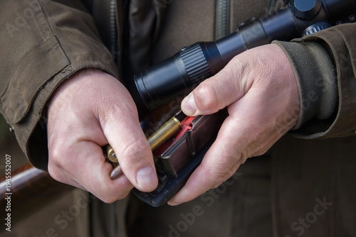 Man with a rifle in his hands.  Close-up of a man loading a carbine with 30-06 cartridges.