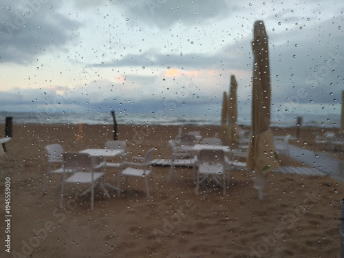 Rainy day at the seaside resort viewed through glass window with raindrops