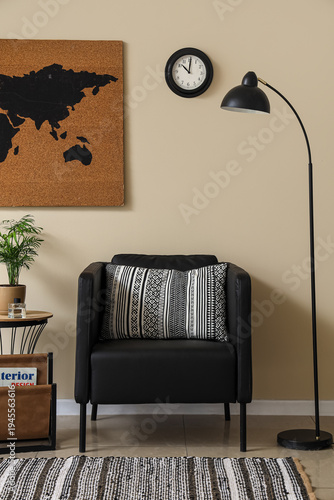 Beautiful living room with black armchair, lamp, coffee table and clock on white wall