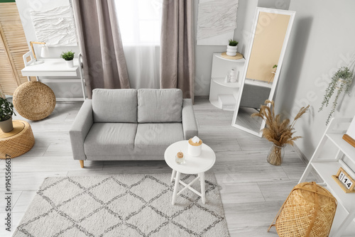 Light stylish living room with grey sofa, coffee table and carpet