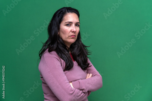 Billede på lærred Woman with dark hair and a serious, annoyed expression, standing with arms cross