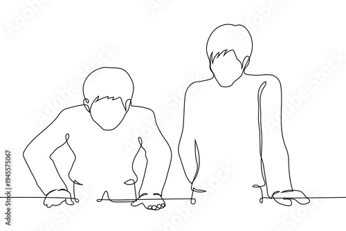 men standing at a desk and looking down, representing collaboration, teamwork