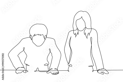 a man and a woman, standing together at a table and looking down, representing collaboration, teamwork,