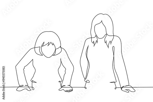 two businesswomen standing at a table and looking down, representing female collaboration, teamwork