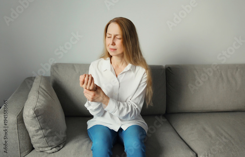 Foto Unhealthy young woman suffers from wrist pain, tunnel syndrome, unwell girl touc