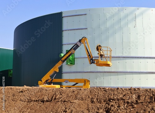 Wallpaper Mural Yellow cherry picker working on the construction of a large industrial tank in the oil industry. Torontodigital.ca