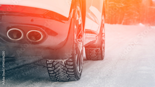 Canvas-taulu Modern car on winter studded tires in the woods on a snowy road