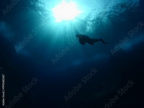 scuba divers exploring underwater with sun beams and rays
