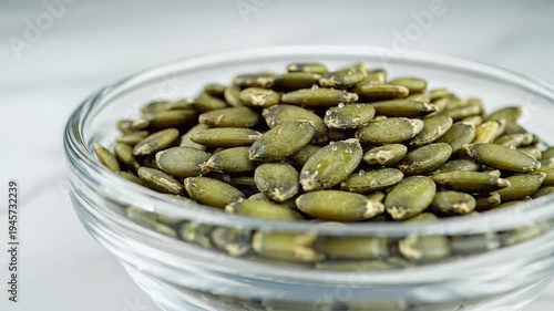 Close up of freshly peeled pumpkin seeds in a clear glass bowl