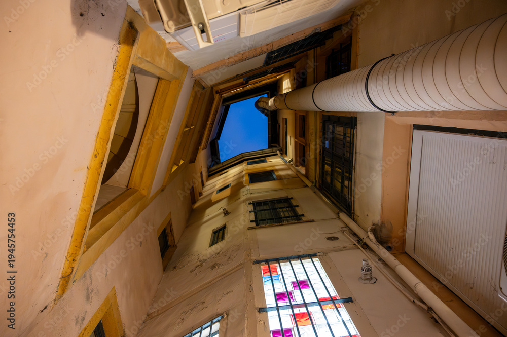 Naklejka premium Lyon, france. December 29, 2023. Historic traboule passage with narrow walls reaching up to a deep blue sky, revealing traditional architecture and heritage