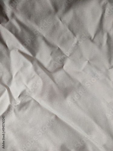 Wrinkled White Fabric on a Flat Surface With Light Shadows and Textures Visible in the Scene