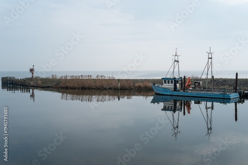 Fishing boat standing reflecting in calm water in medemblik