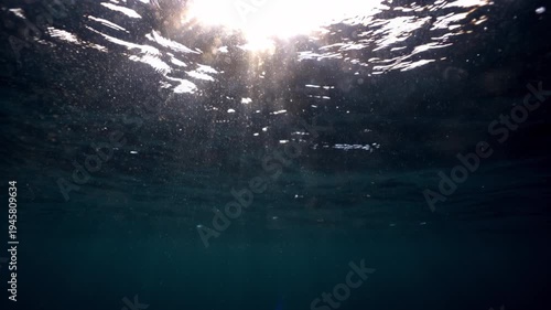 Underwater light creates a beautiful veil, consisting of sunlight. Underwater ocean waves oscillate and flow with the rays of light. Copy space background. Beautiful blue calm wave sparkling