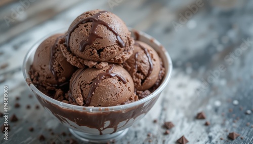 Delicious Scoops of Chocolate Ice Cream with Drizzle in a Clear Bowl on Rustic Wooden Table