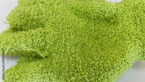 Close-up of a green microfiber cloth with a soft texture and clearly visible fiber details. Suitable for cleaning concepts, household items, cleaning supplies, and textured backgrounds.