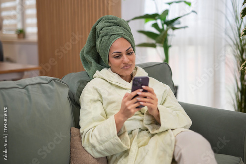 Fotografie Woman relaxing at home checking smartphone messaging