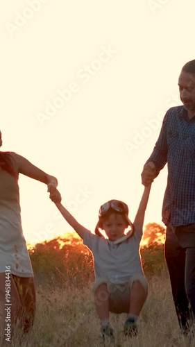 Family with son walking on field on wind farm. Happy Family and son playing at the Wind turbines generating electricity. Family time together.