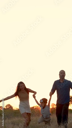 Family with son walking on field on wind farm. Happy Family and son playing at the Wind turbines generating electricity. Family time together.