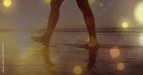 Konstfotografi Wading woman's barefoot legs and feet making ripples in shallow seawater on beac
