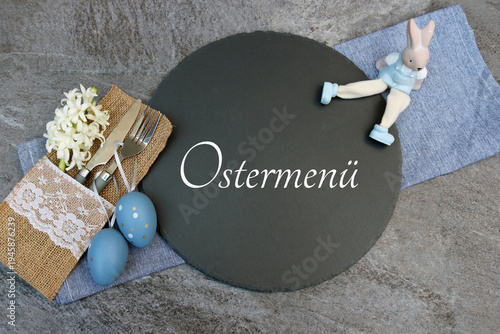 Gedeckter Ostertisch mit Osterdekoration und einer Schieferplatte mit der Beschriftung Ostermenü.