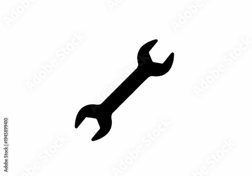 A wrench lies on a flat surface indoors.