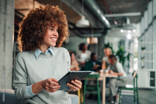 Businesswoman standing in modern office holding tablet smiling