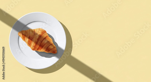 top view of fresh golden croissant on white plate with window shadow on yellow background and copy space