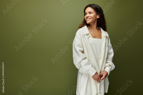 Fotografija Beautiful young woman smiling gracefully in a cozy white outfit against a soothi
