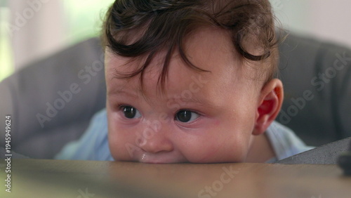 Baby lying on dining table, biting surface, big-eyed expression, early childhood sensory exploration, teething behavior, curious moment of discovery, indoor home setting