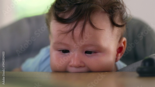 Bild auf Leinwand Baby lying on dining table, biting surface, big-eyed expression, early childhood