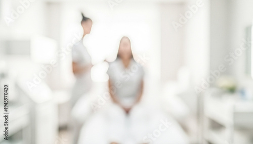 A blurred image depicting a woman receiving a treatment in a spa-like environment, emphasizing relaxation and pampering in a white, bright setting.