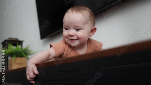 Close-up of a smiling infant on a cabinet, looking sideways and drooling heavily