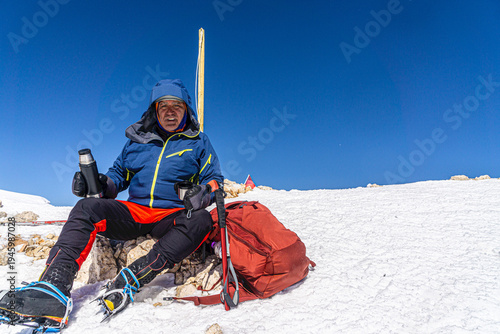 The alpinist is enjoying the coffee at the summit of Kızlarsivrisi mountain (3070 m.) in Antalya, Turkey