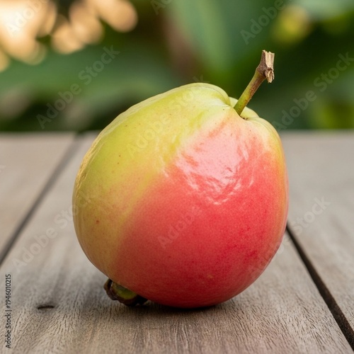 Ripe Guava Icon of Gradient Green to Pink Fruit with Stem on Wooden Surface and Foliage Background for Tropical or Agricultural Themes