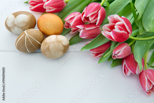 Easter background with bouquet of pink tulips and colorful eggs .