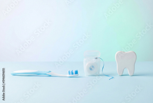 Toothbrush, dental floss and tooth model on blue background, oral hygiene and dental care concept