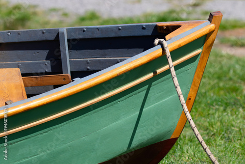 Close up of green painted row boat's wooden bow with white rope line