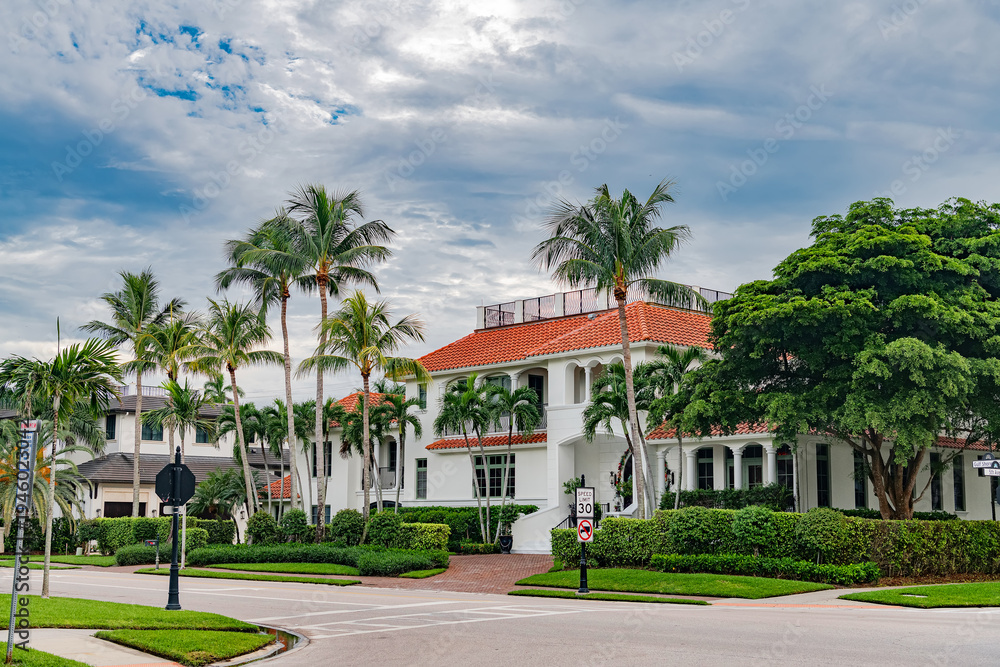 Fototapeta premium Luxury tropical house with palm trees and red tile roof in Naples Florida residential neighborhood