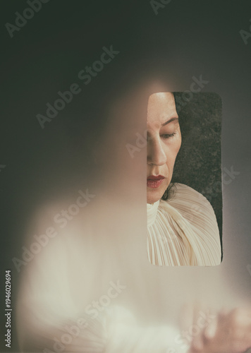 woman in beige blouse behind an opaque screen with opening XII