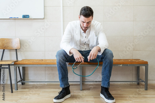 A tired doctor sits alone on a bench in the hallway after a long and demanding day. The quiet moment shows exhaustion and reflection after caring for many patients.	
