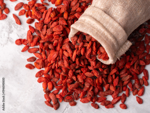 Cuadro en lienzo Dried Goji berries or Wolfberry scattered, vibrant red, in a wooden bowl on a textured background