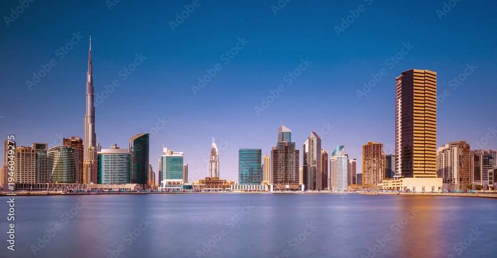 Obraz premium Panoramic skyline of Dubai with modern skyscrapers and futuristic architecture at sunset. Iconic cityscape of the largest city in the United Arab Emirates, famous for luxury tourism, business district