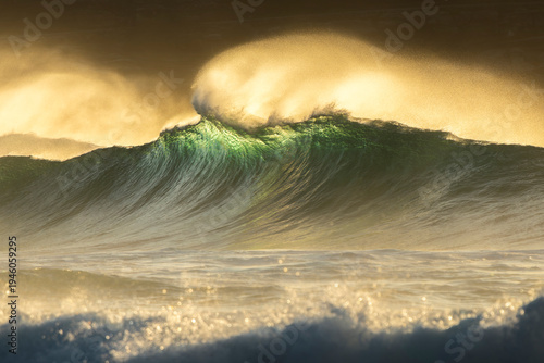 Ocean wave captured with slow shutter speed creating motion blur effect in golden light along the coast of Sydney, Australia.