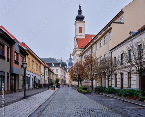 Фотография Historic Trnava Slovakia Street With Cobblestones And Classic Church Tower